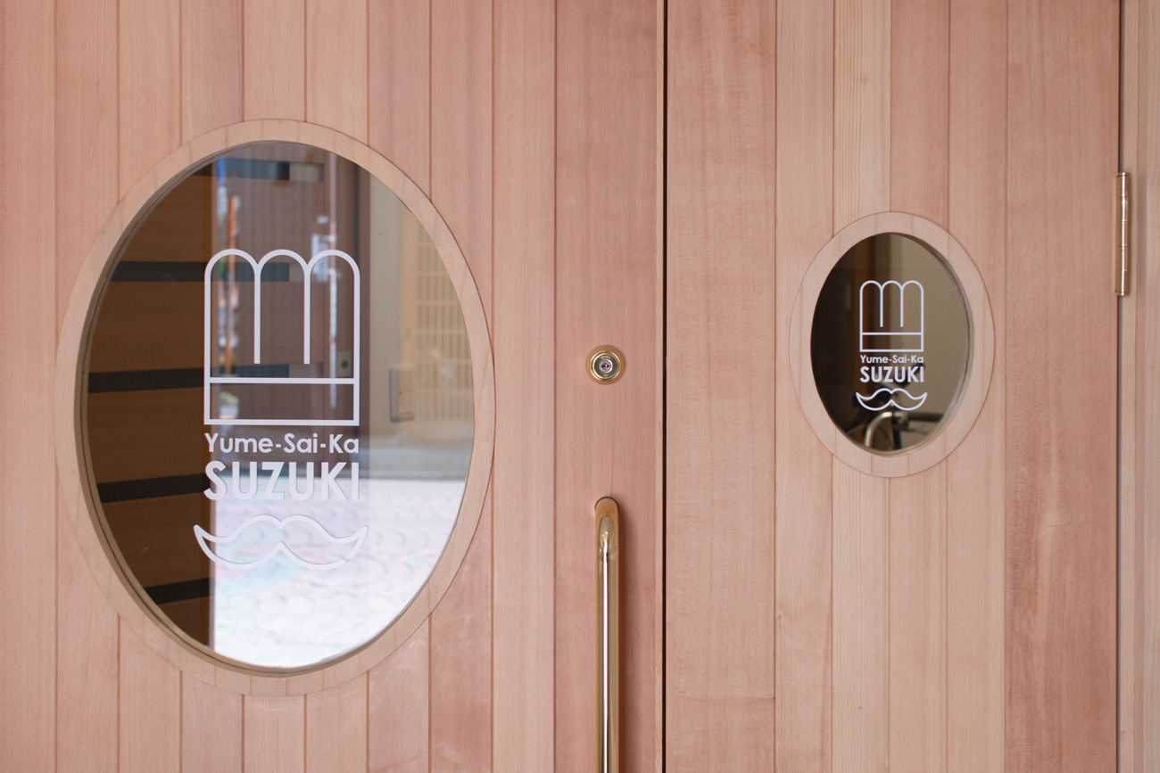 すずきさんのロゴをあしらった玄関の木製扉